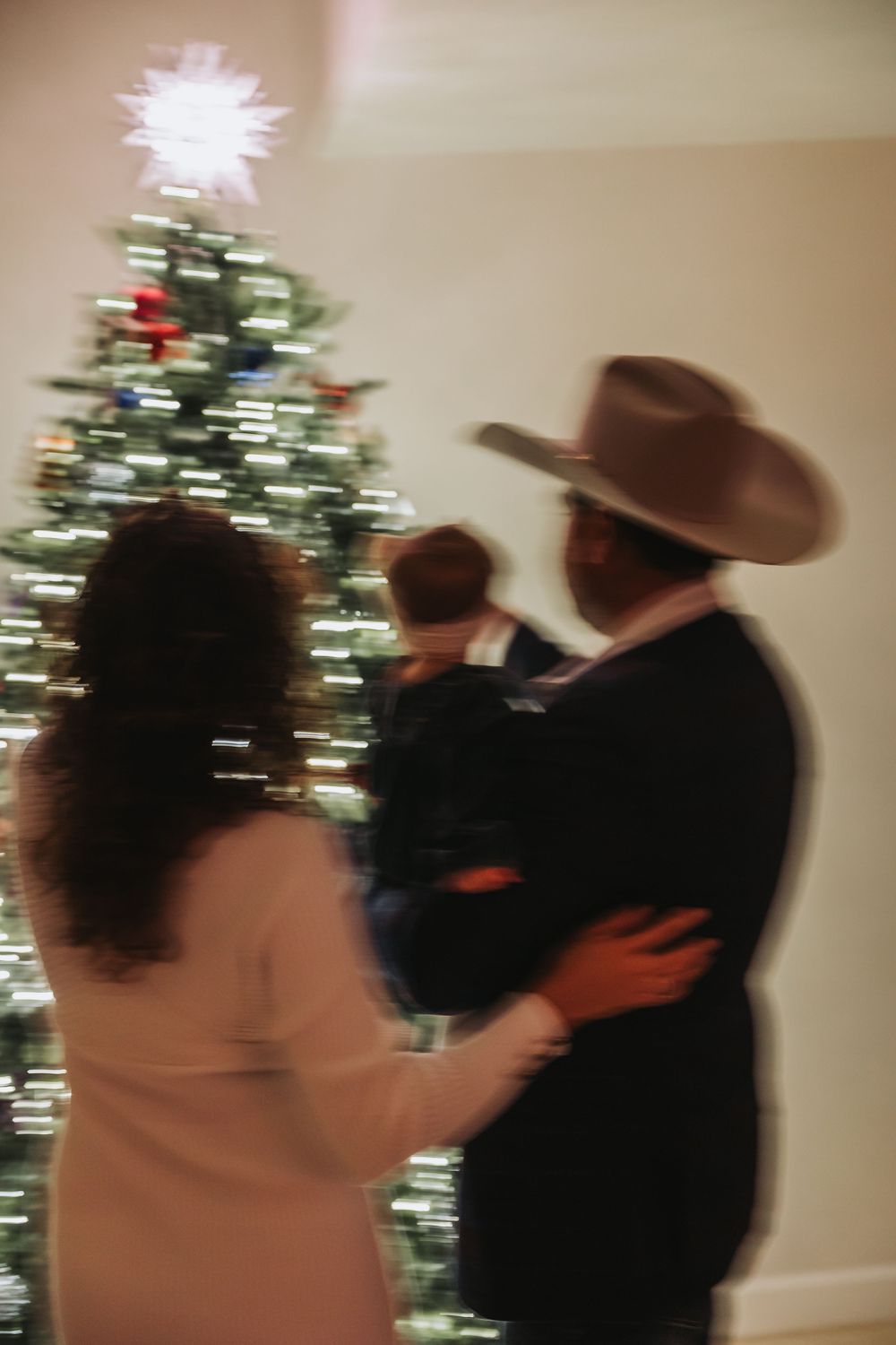 A couple in western attire dancing together in front of a decorated Christmas tree.