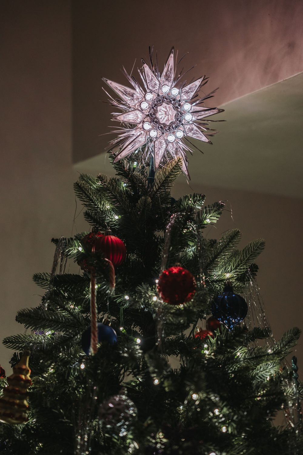 A series of photos showing a glowing starburst Christmas tree topper illuminated against an evergreen tree with ornaments.