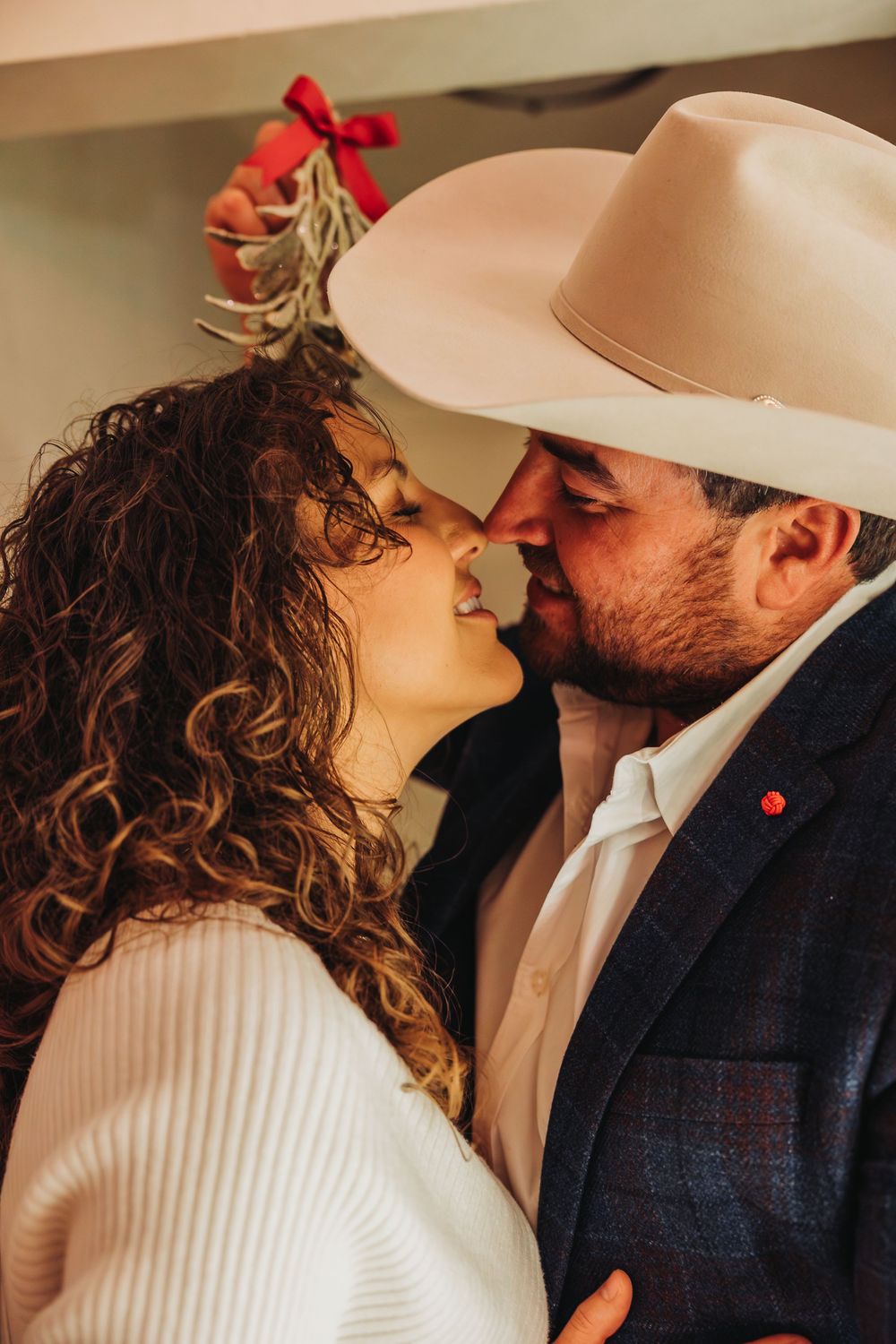 A romantic moment between a couple with one wearing a cowboy hat and the other in a white sweater.