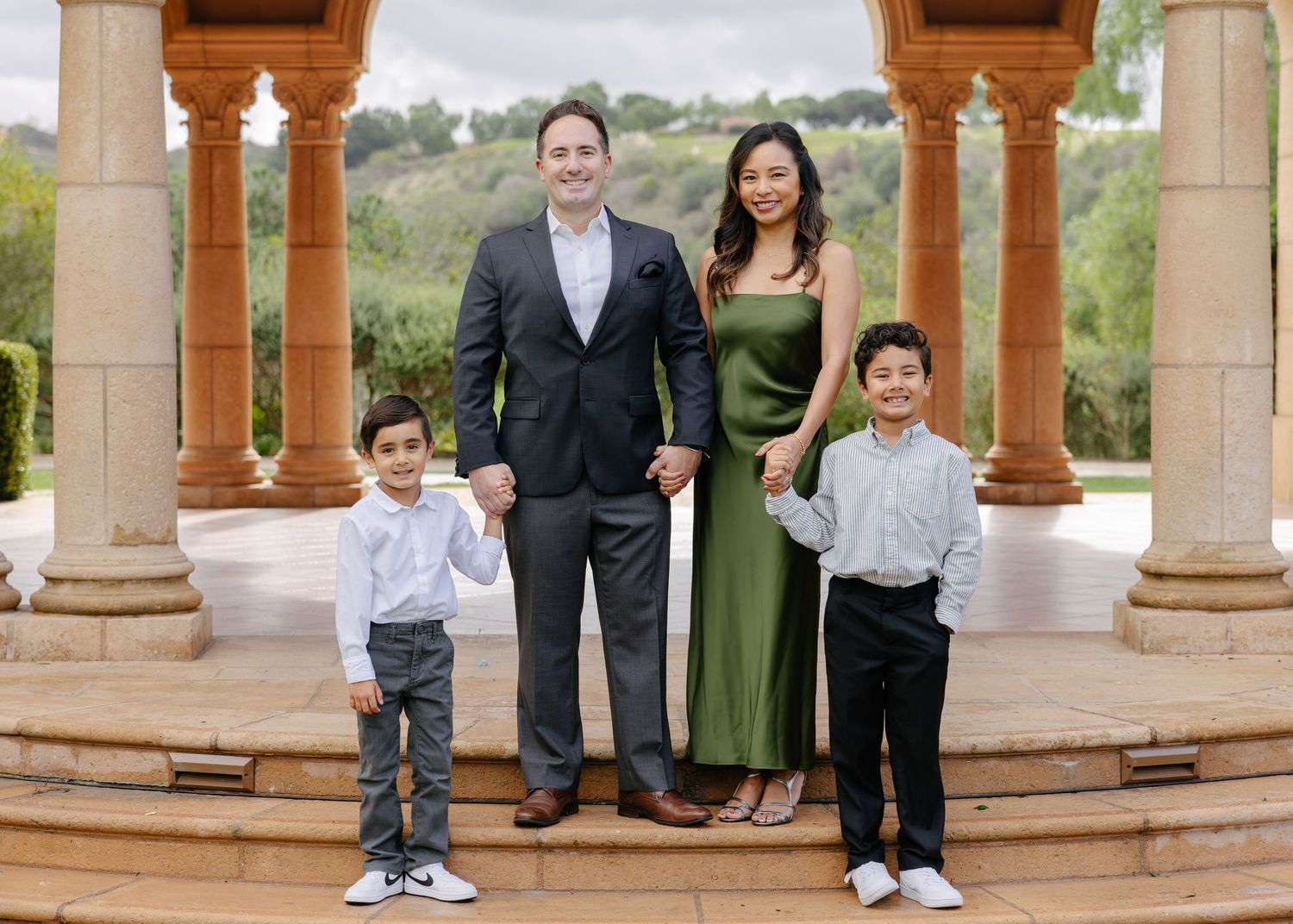 A series of outdoor photos showing a family gathering under a stone gazebo with pillars in a garden setting.