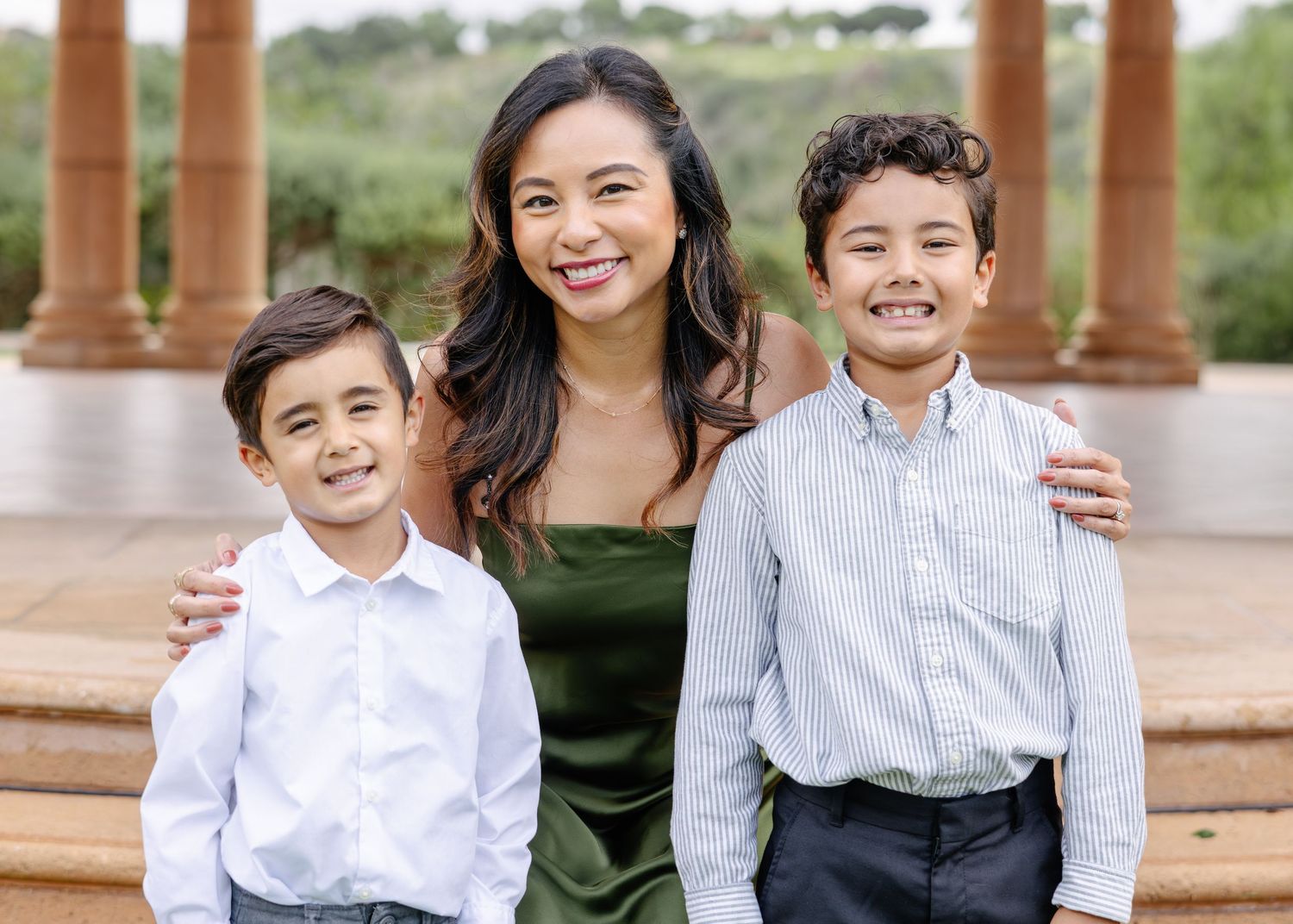 A group poses together outdoors against a natural backdrop with trees and greenery.