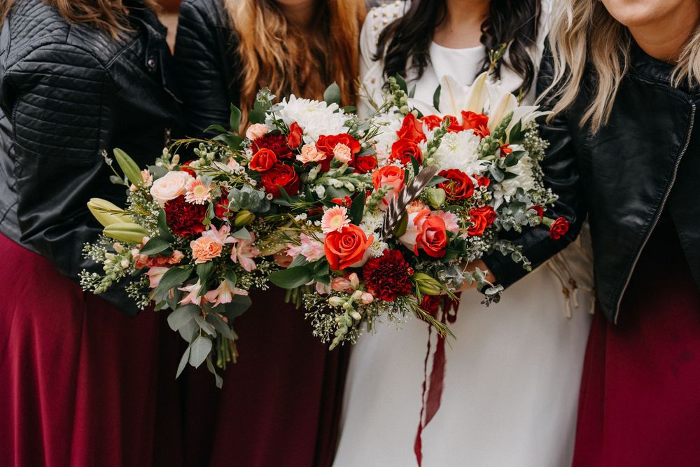 Elegant floral bouquets featuring deep red roses and white flowers create a romantic wedding display.