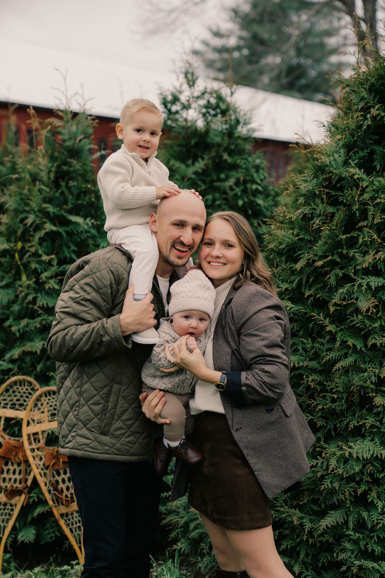 A family shares joyful moments together among evergreen trees on an overcast day.