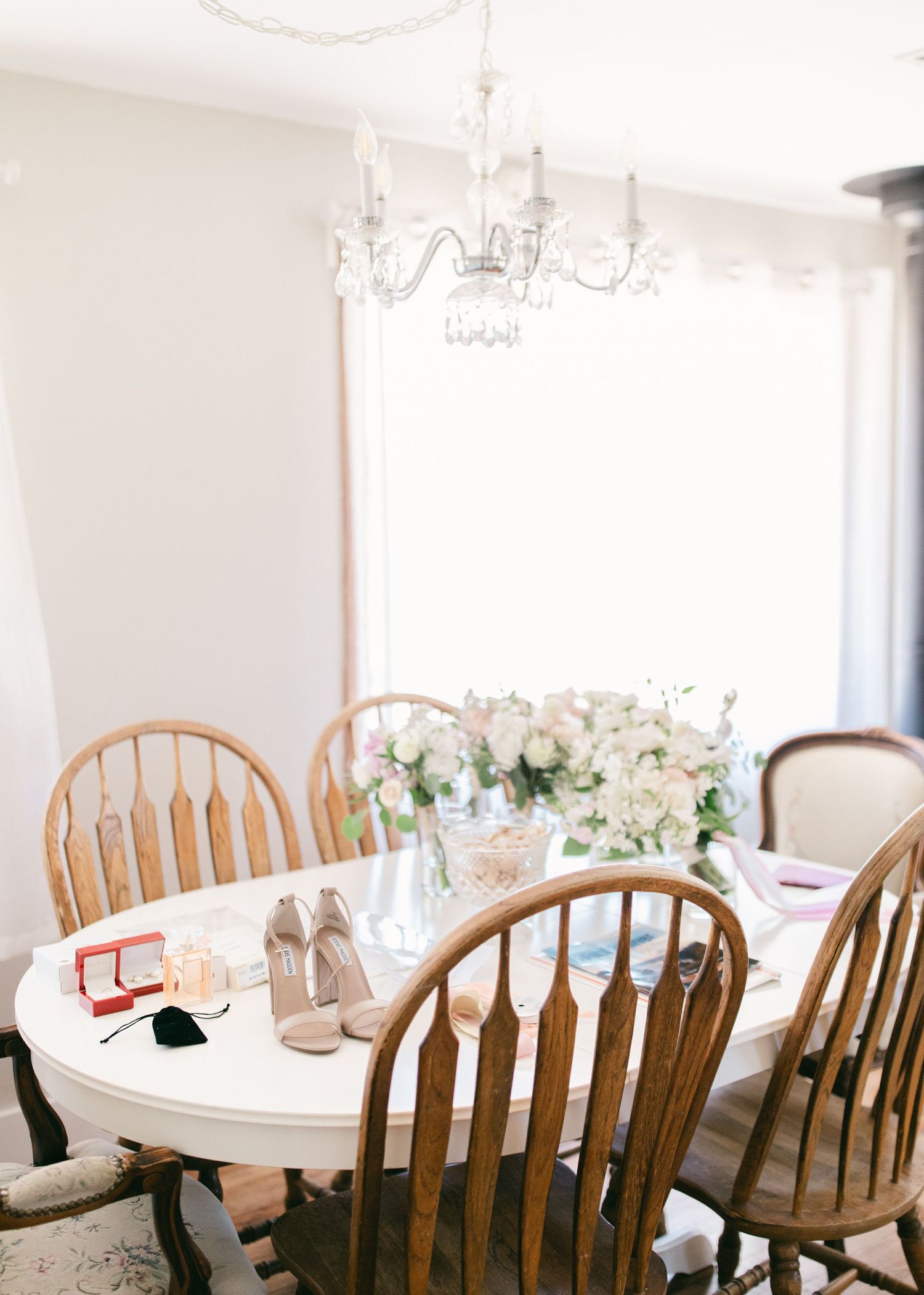 Elegant dining room with white walls, crystal chandelier, wooden chairs, and round tables set for a formal event.