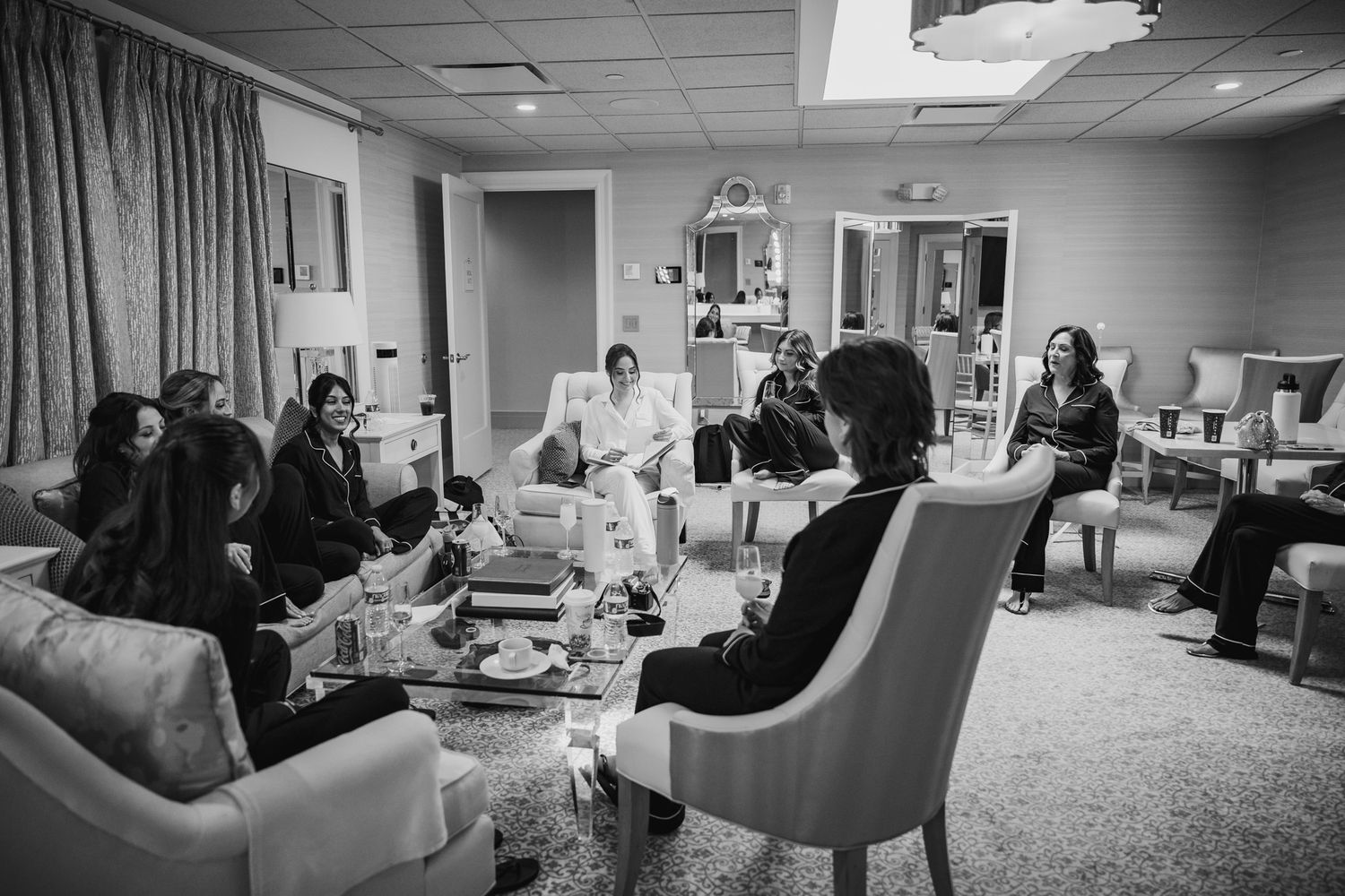 Wedding party relaxing in a bridal suite with comfortable seating and natural lighting.