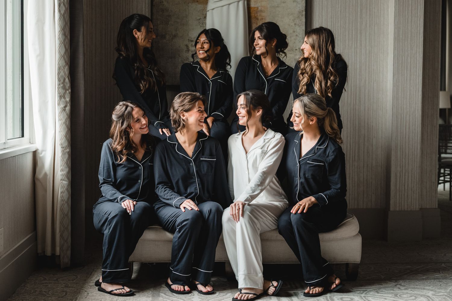 Bridesmaids in matching robes sitting together during wedding day preparations.