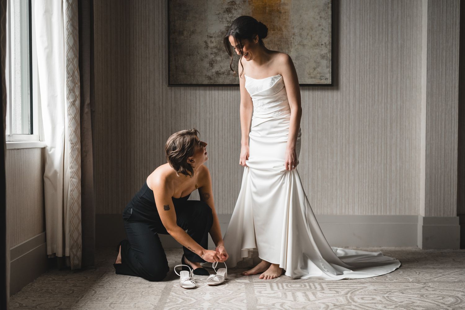 Getting ready sequence showing final wedding dress adjustments in a bright interior.