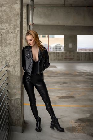girl posing in parking garage leaning on concrete pillar