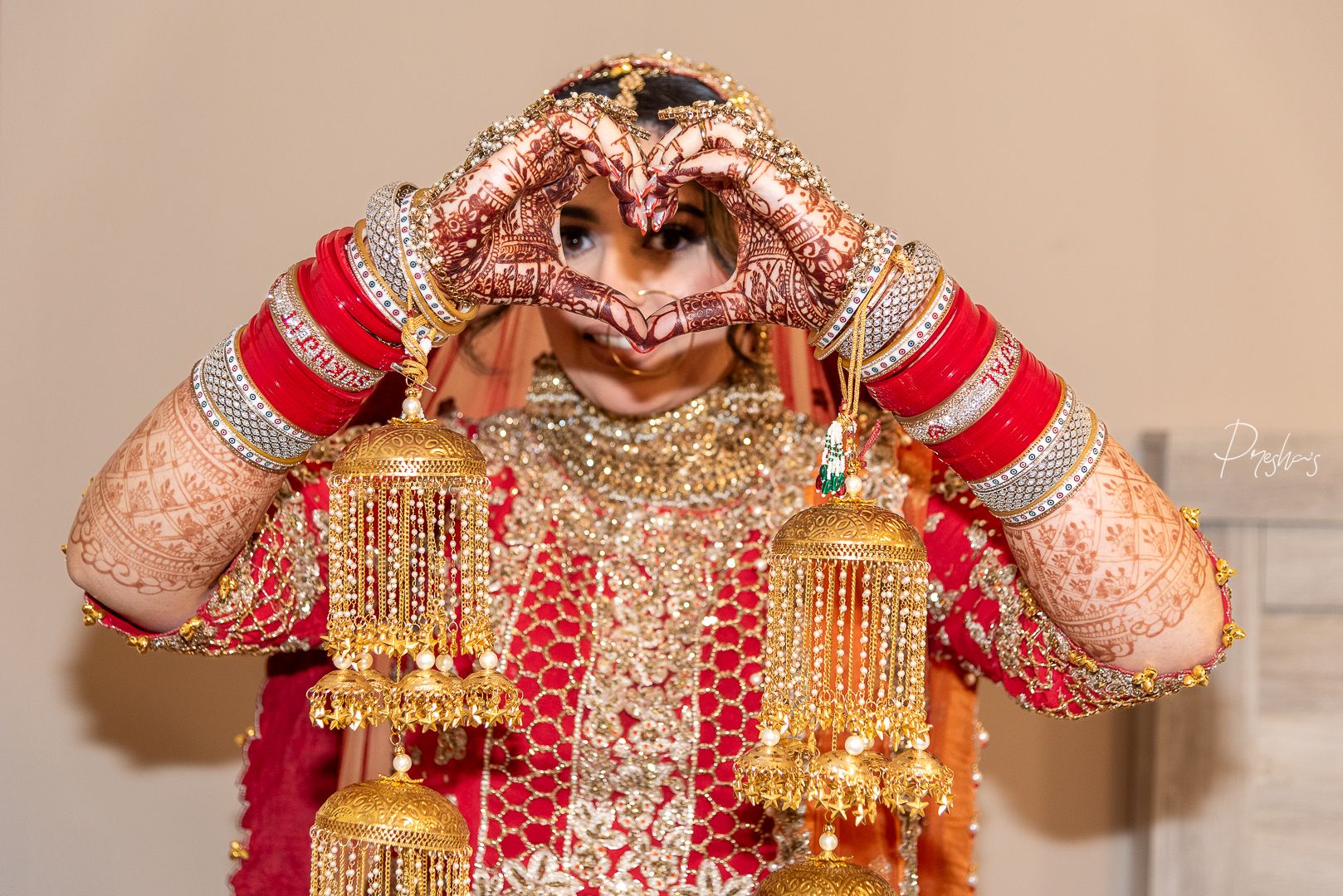 Bride showing heart for groom. Special day for bride. Candid moment of Indian bride in red bridal lehenga.