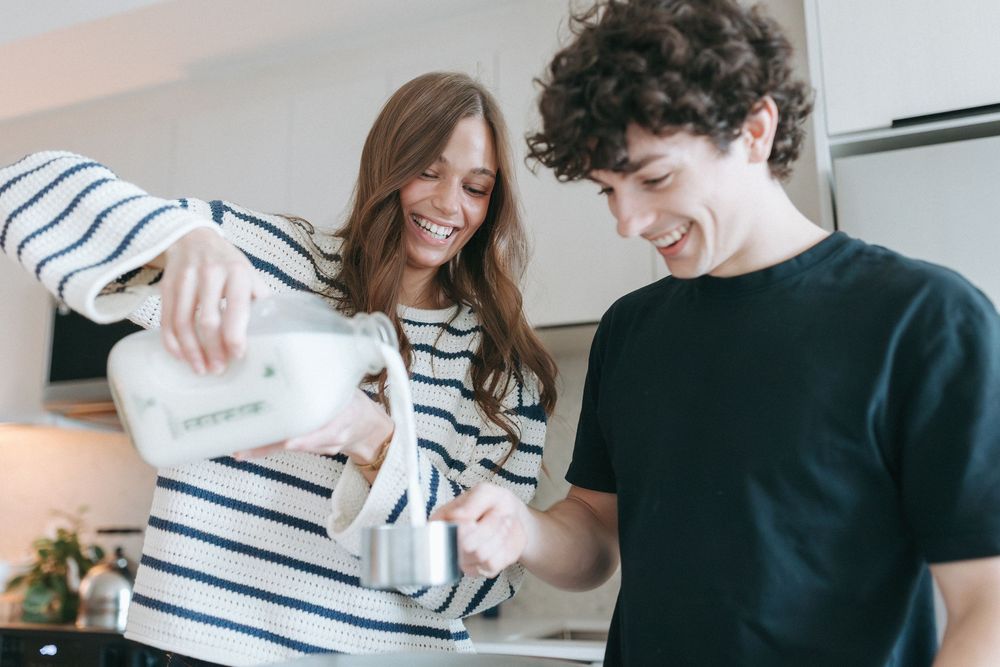 Couple preparing food together in bright modern kitchen with striped sweater.