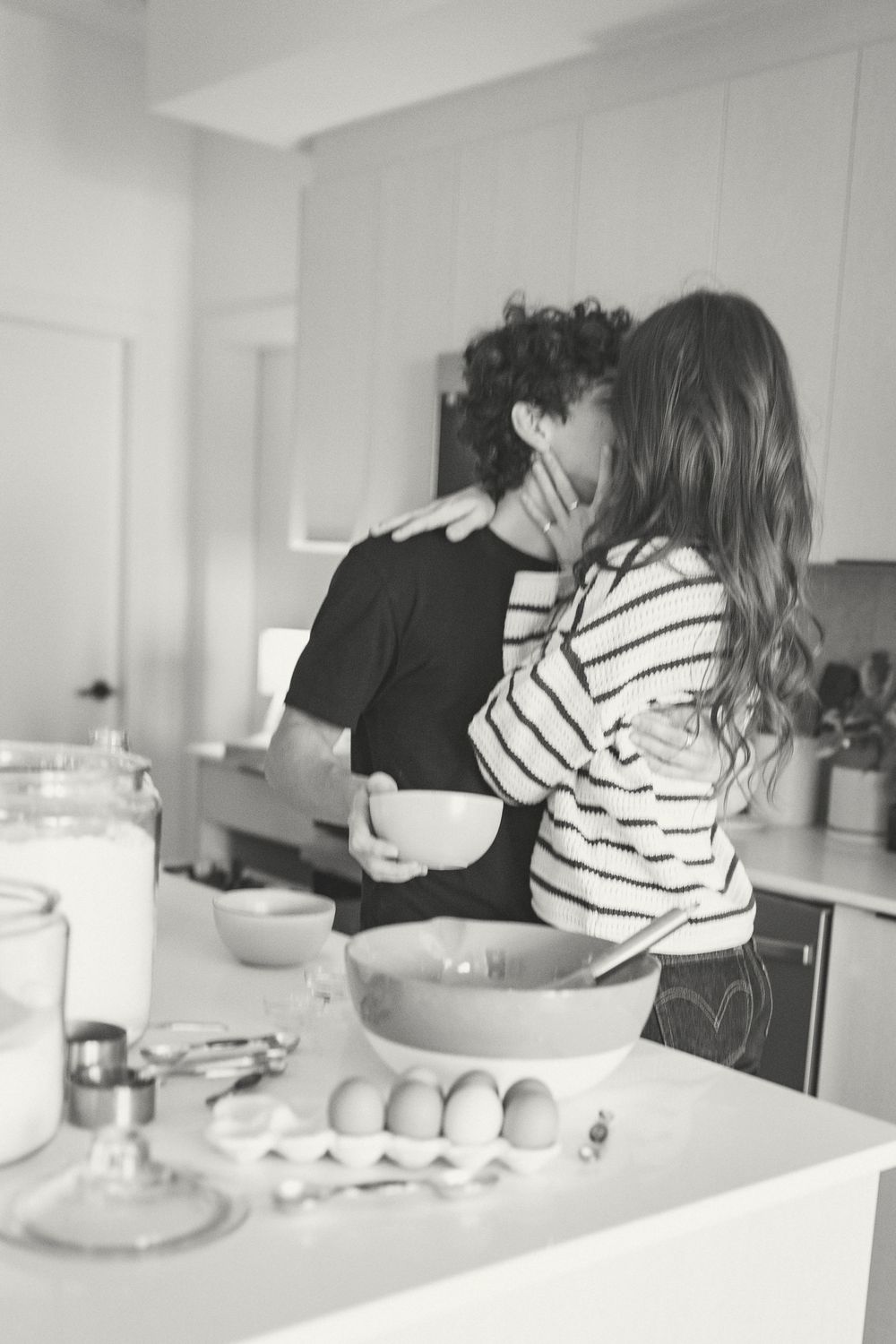 Series of black and white kitchen photos showing romantic moments between two people near a counter.