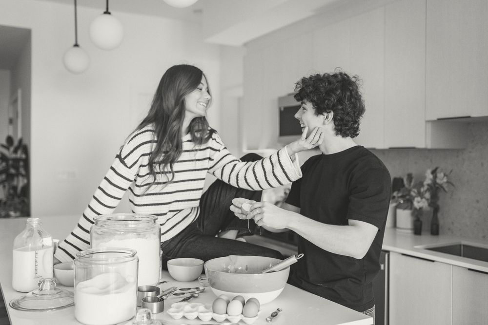 Couple sharing intimate moment while baking in modern white kitchen.