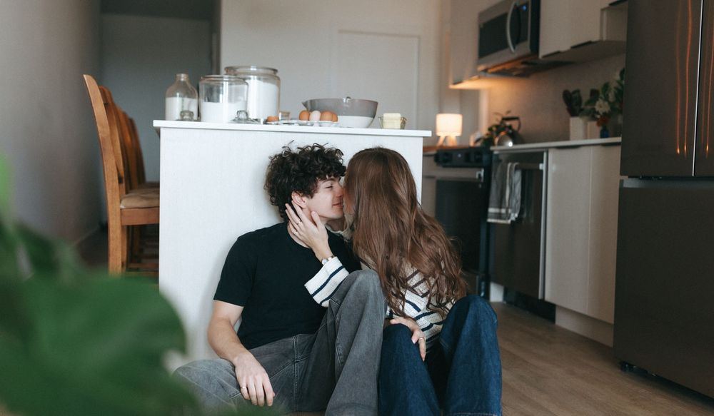 Cozy kitchen scene with two people baking together near houseplants.