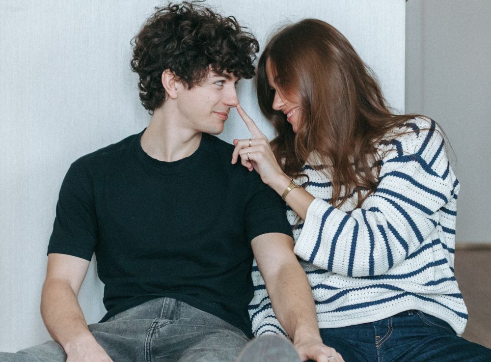 A couple relaxes together on a couch in a minimalist white interior setting.