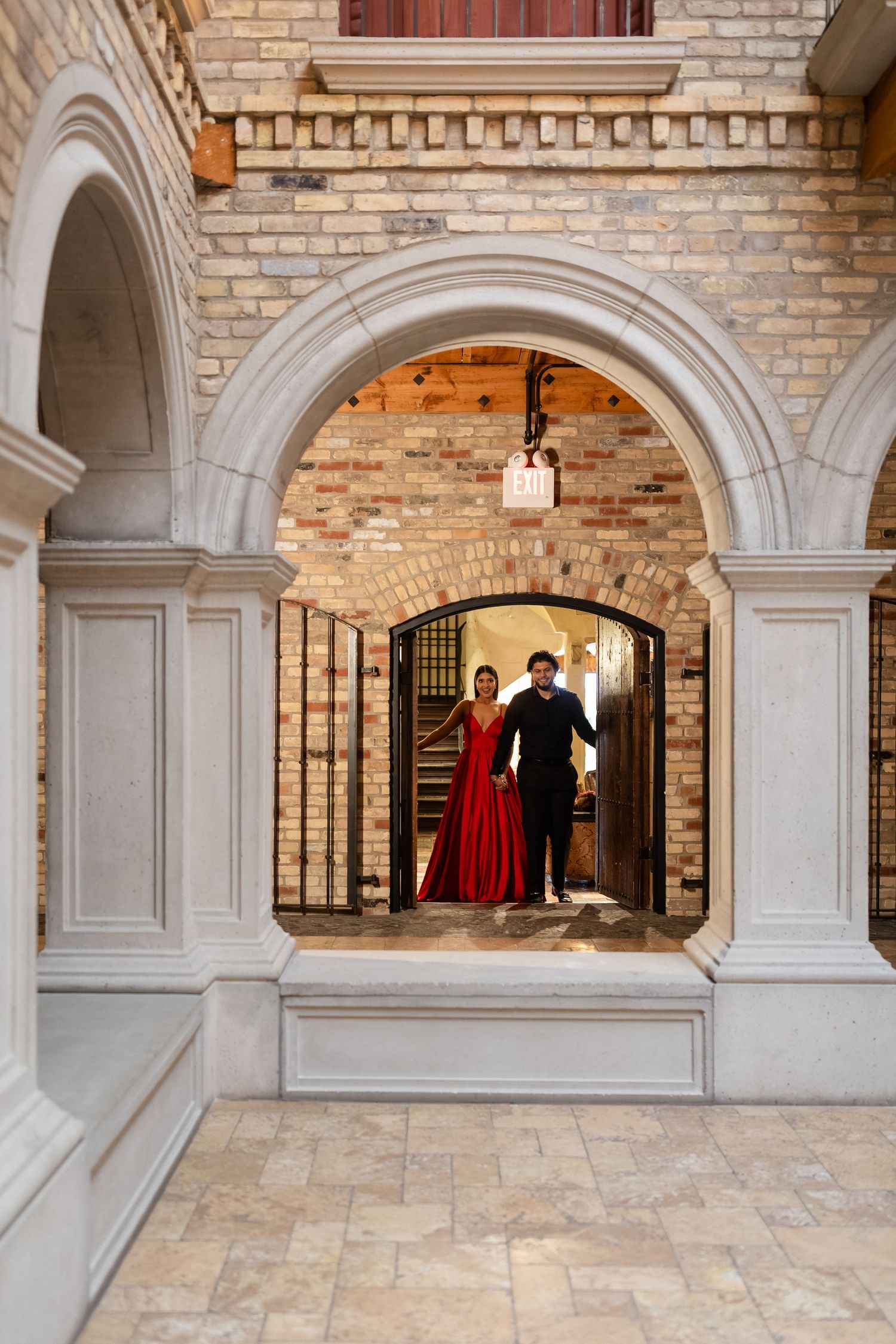 White stone archways and exposed brick walls create an elegant corridor in a historic building interior.