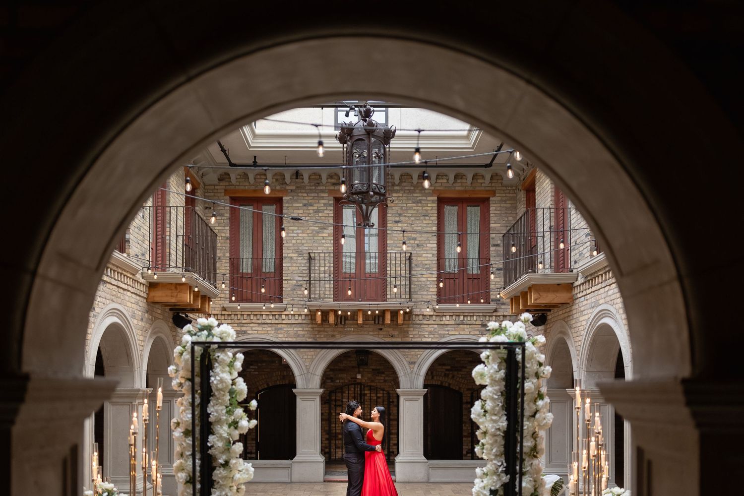 Elegant arched colonnade in historic building decorated with white floral arrangements and candles.