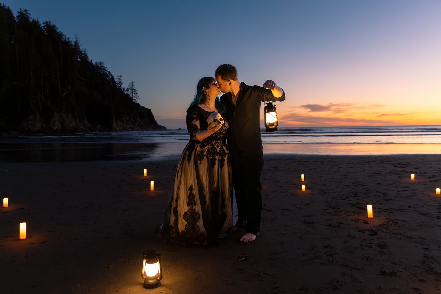 Couple shares a romantic kiss at sunset on a candlelit Oregon Coast holding vintage lanterns.