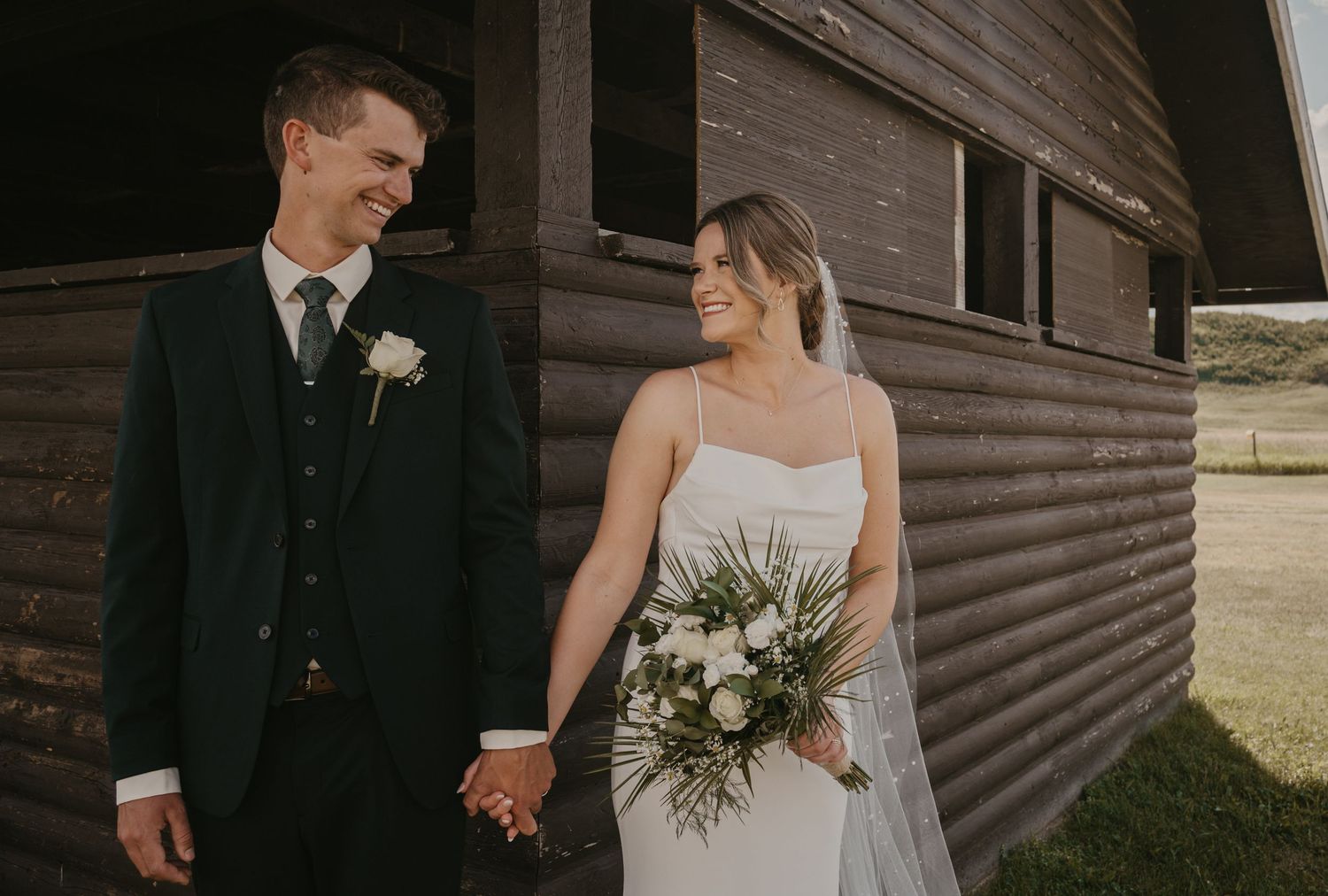 A wedding couple holds hands while walking together on a rustic wooden porch during their special day.