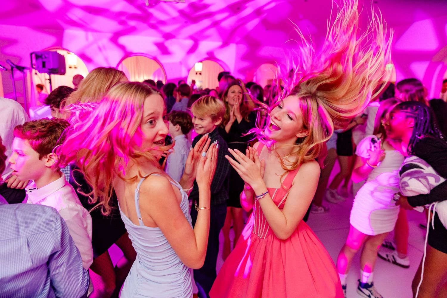 Energetic nightclub scene with purple lighting and crowd dancing beneath balloons.
