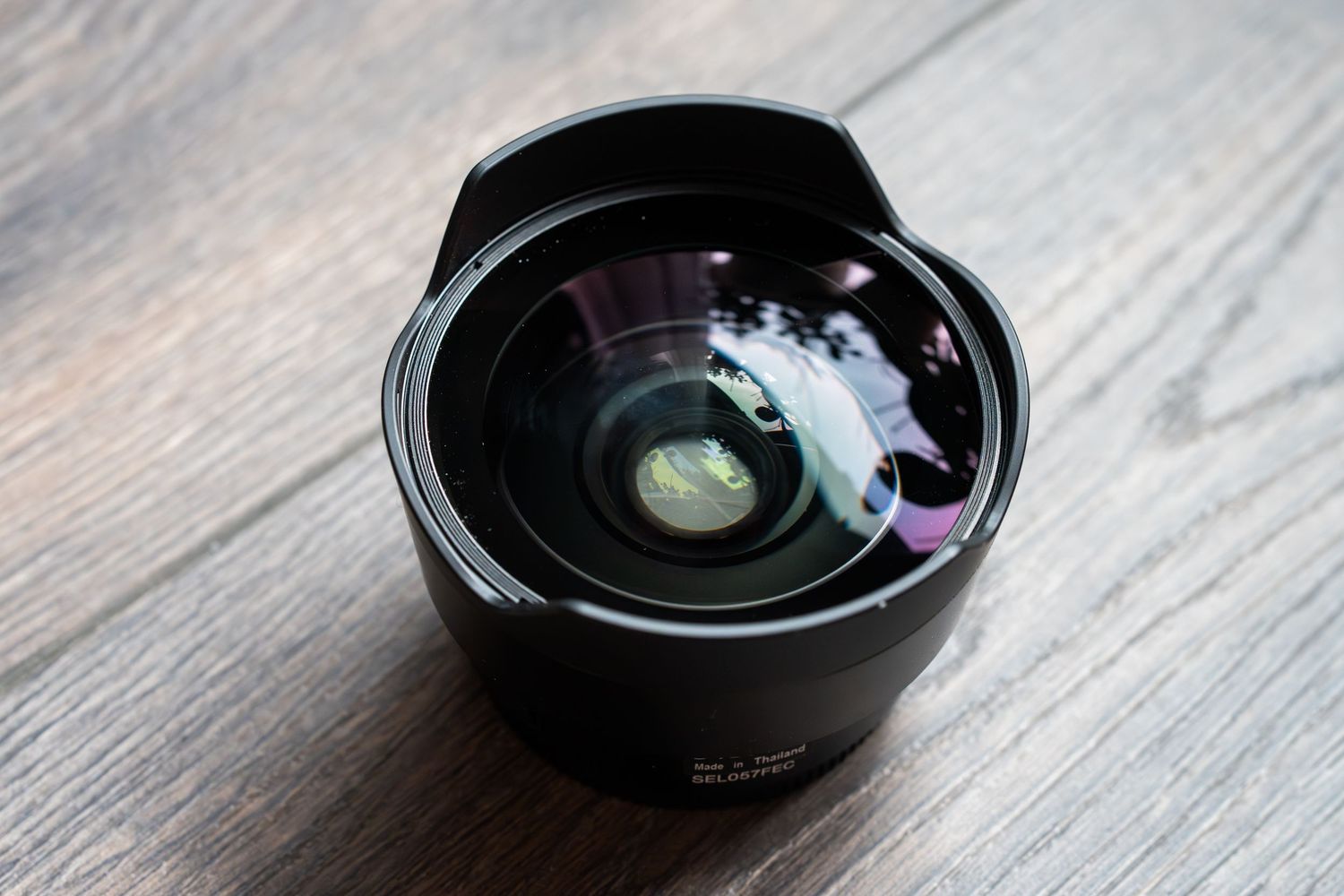 Seven camera lenses shown in a row on a gray wooden surface with shallow depth of field.