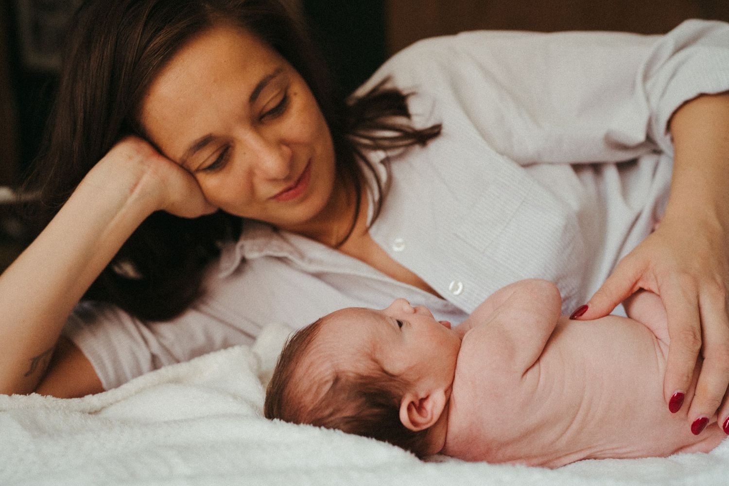 Intimate moment between mother and newborn baby on bed.