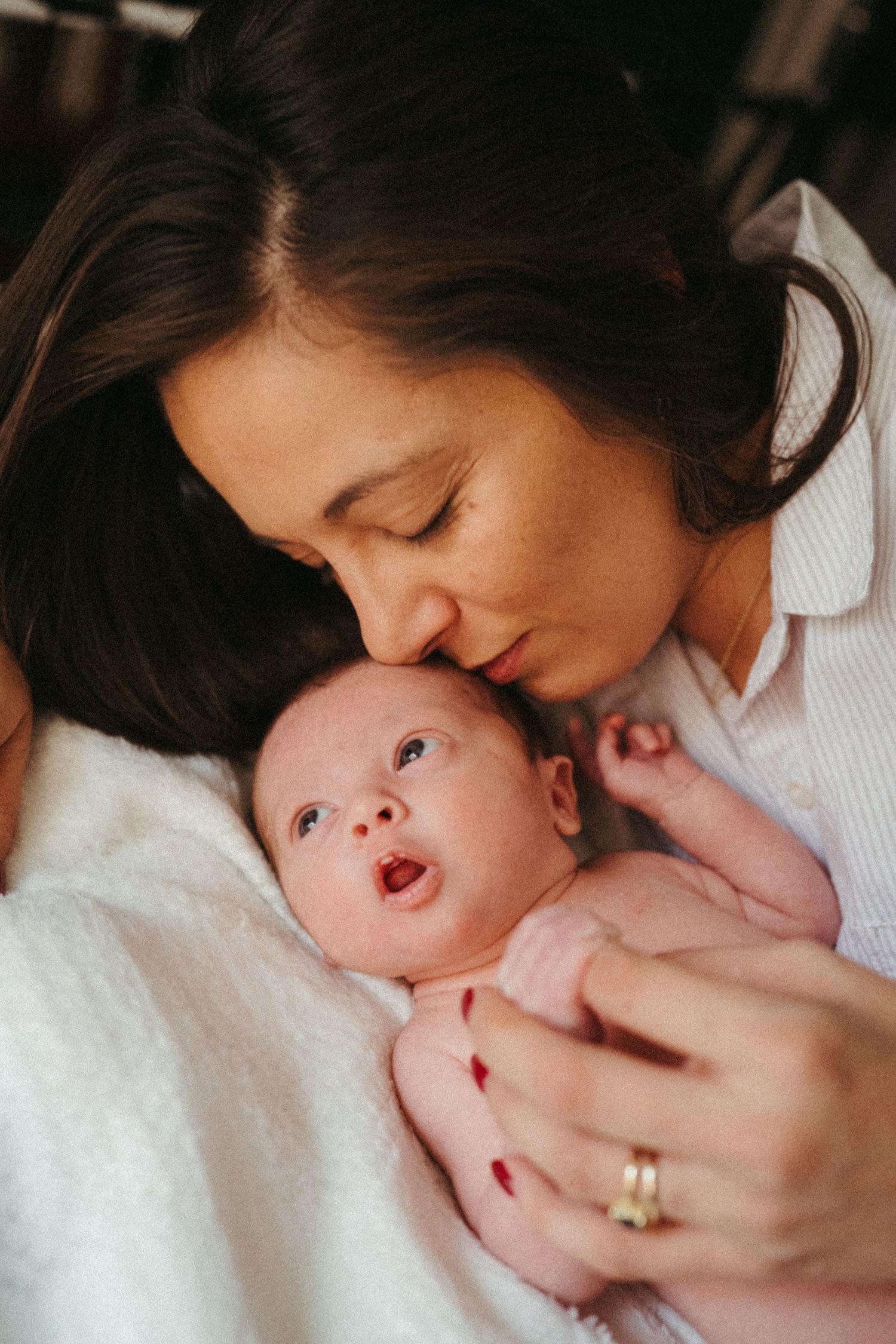 Tender moment between parent and newborn baby against white background in soft lighting.