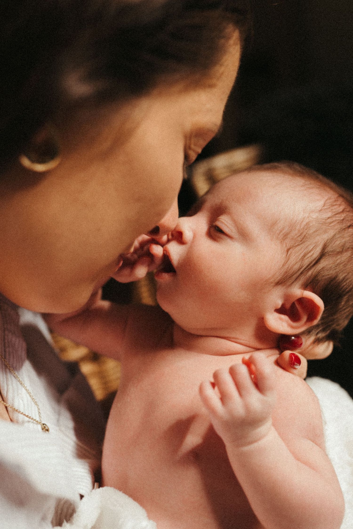 Close-up series of loving parent nuzzling with baby in warm lighting.