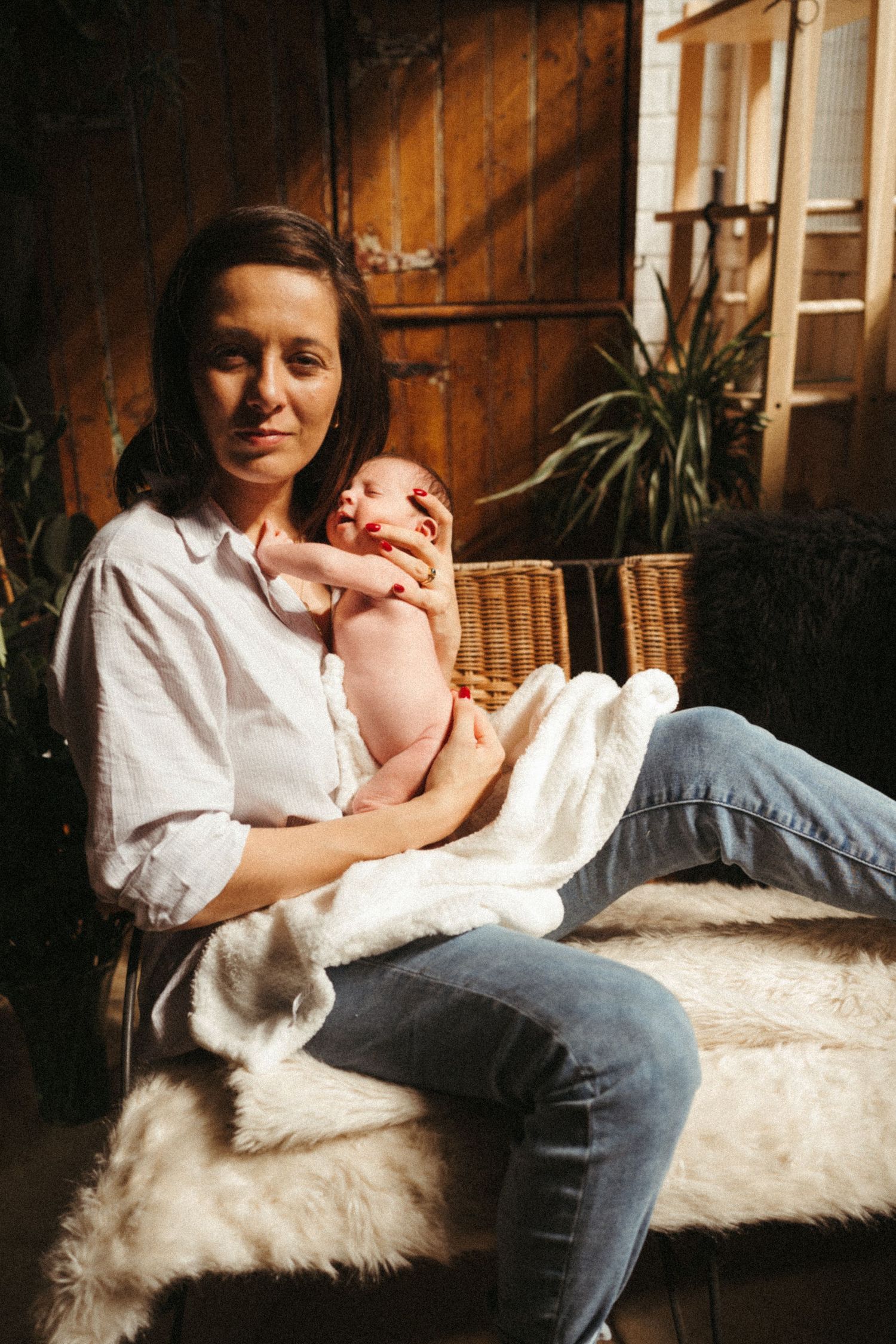 Parent in casual attire bonding with baby on furry white couch in rustic setting.