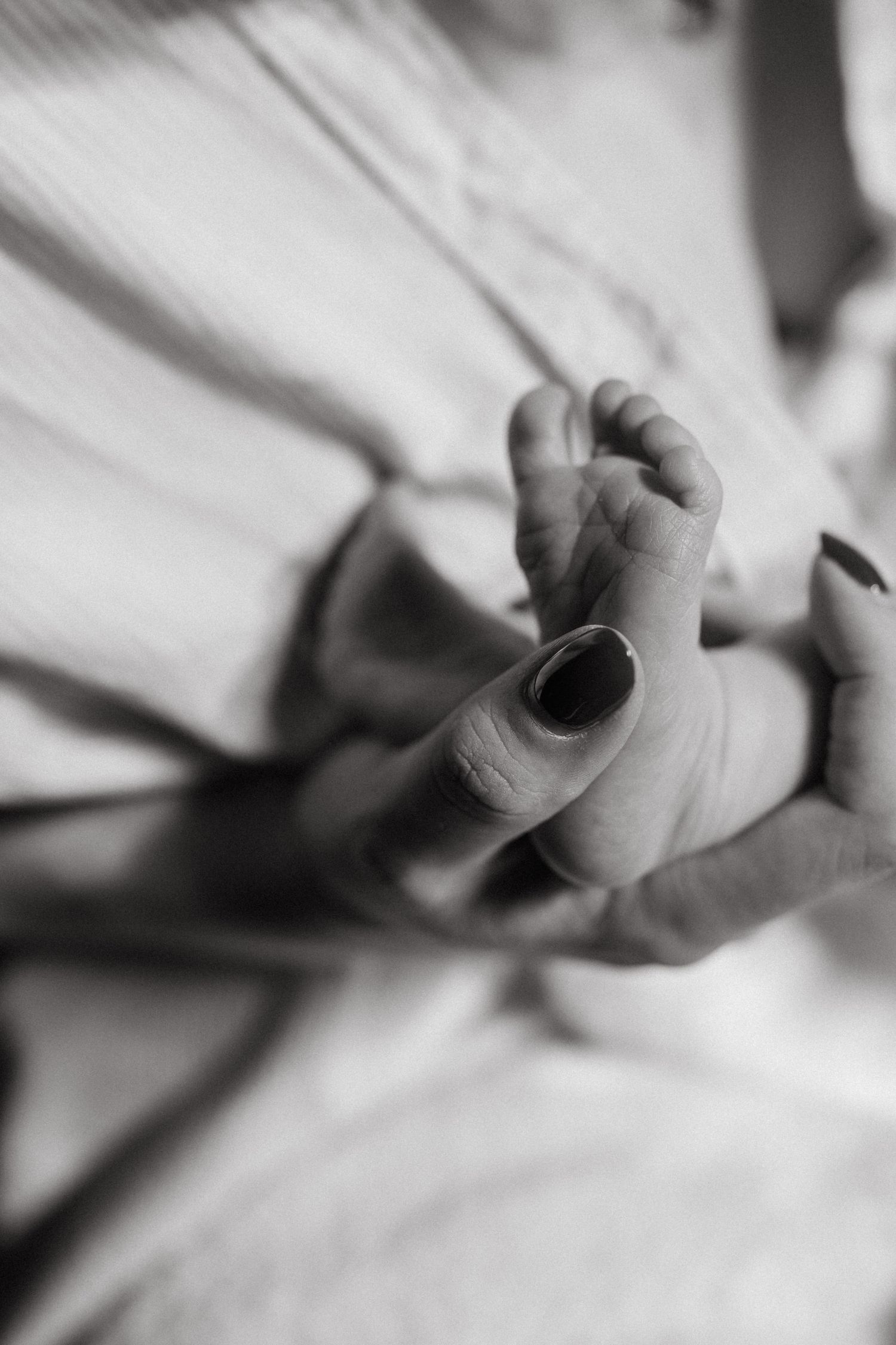 Close-up sequence of tiny newborn fingers grasping in black and white.