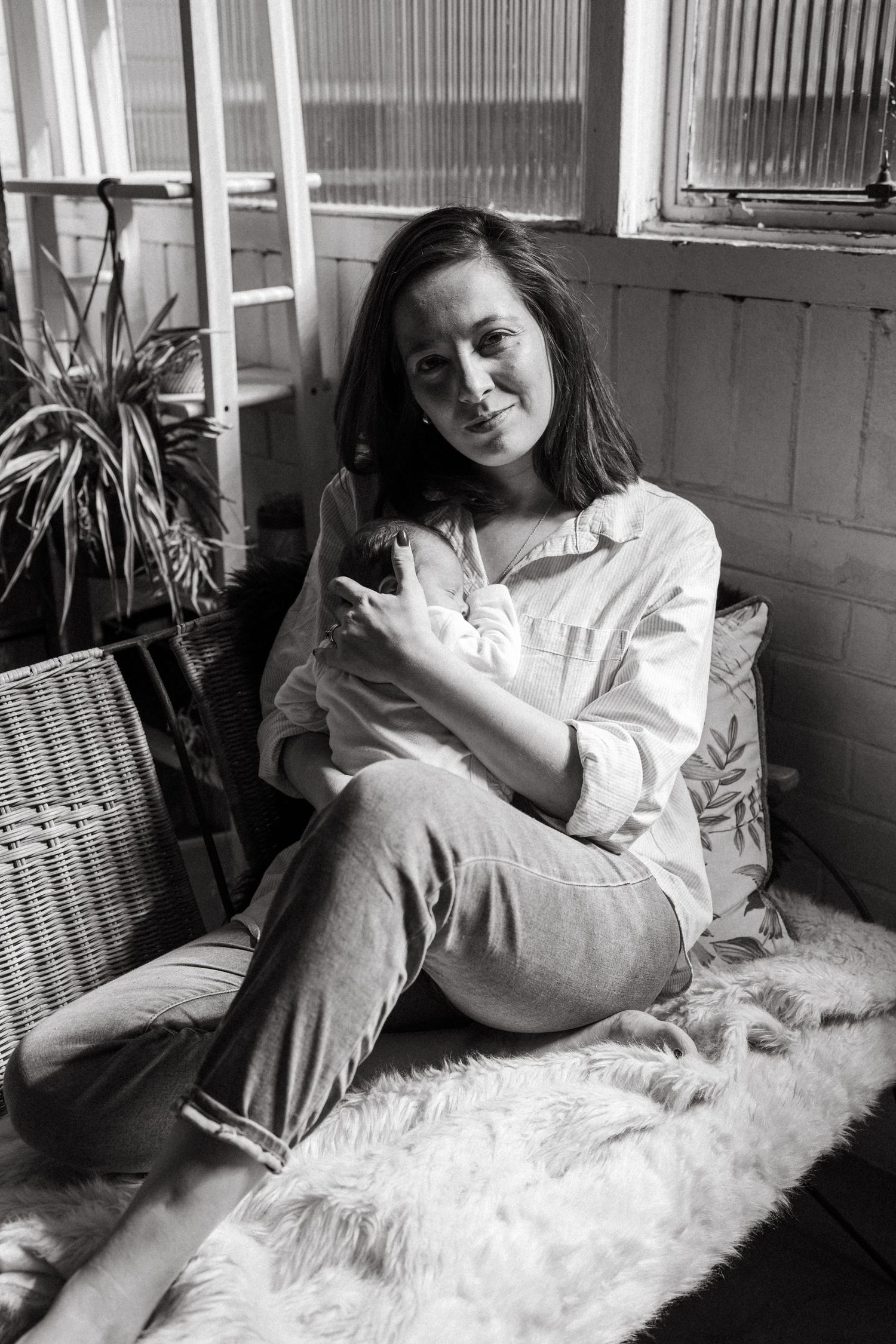 Intimate black and white portraits of mother and baby resting on plush surface.