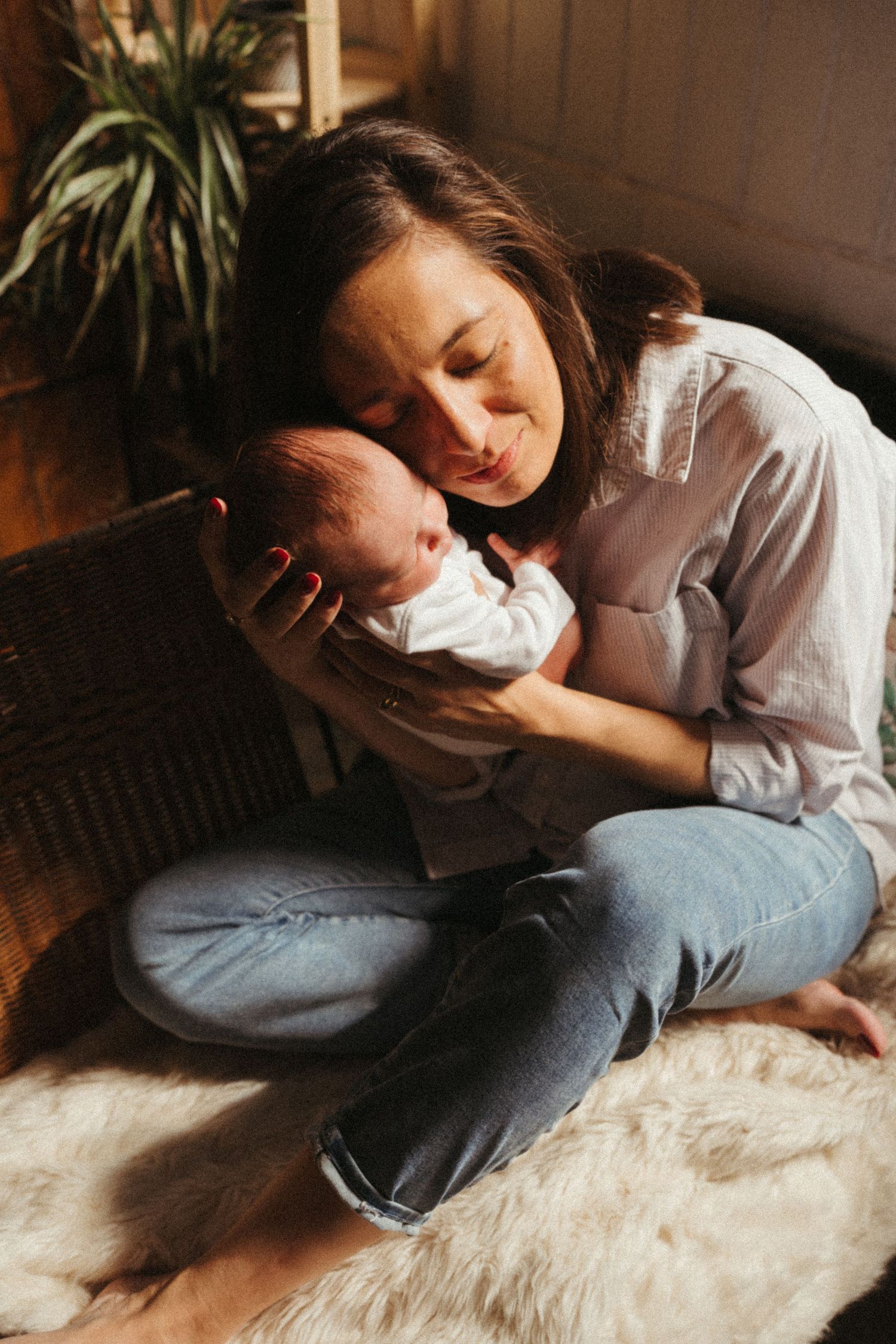 Intimate moments of mother and baby resting on fluffy white rug.
