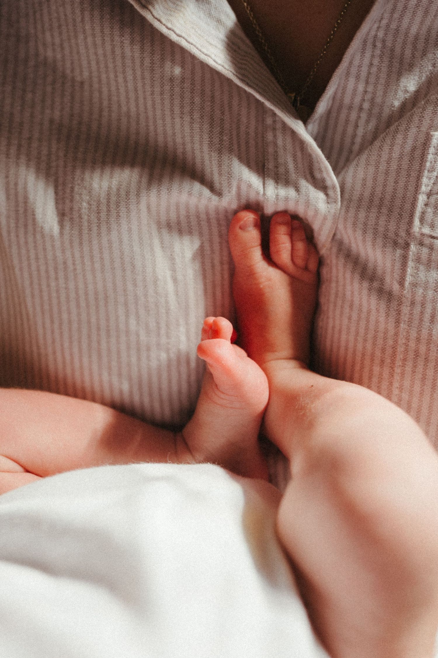 Close-up of tiny baby feet against soft striped fabric.