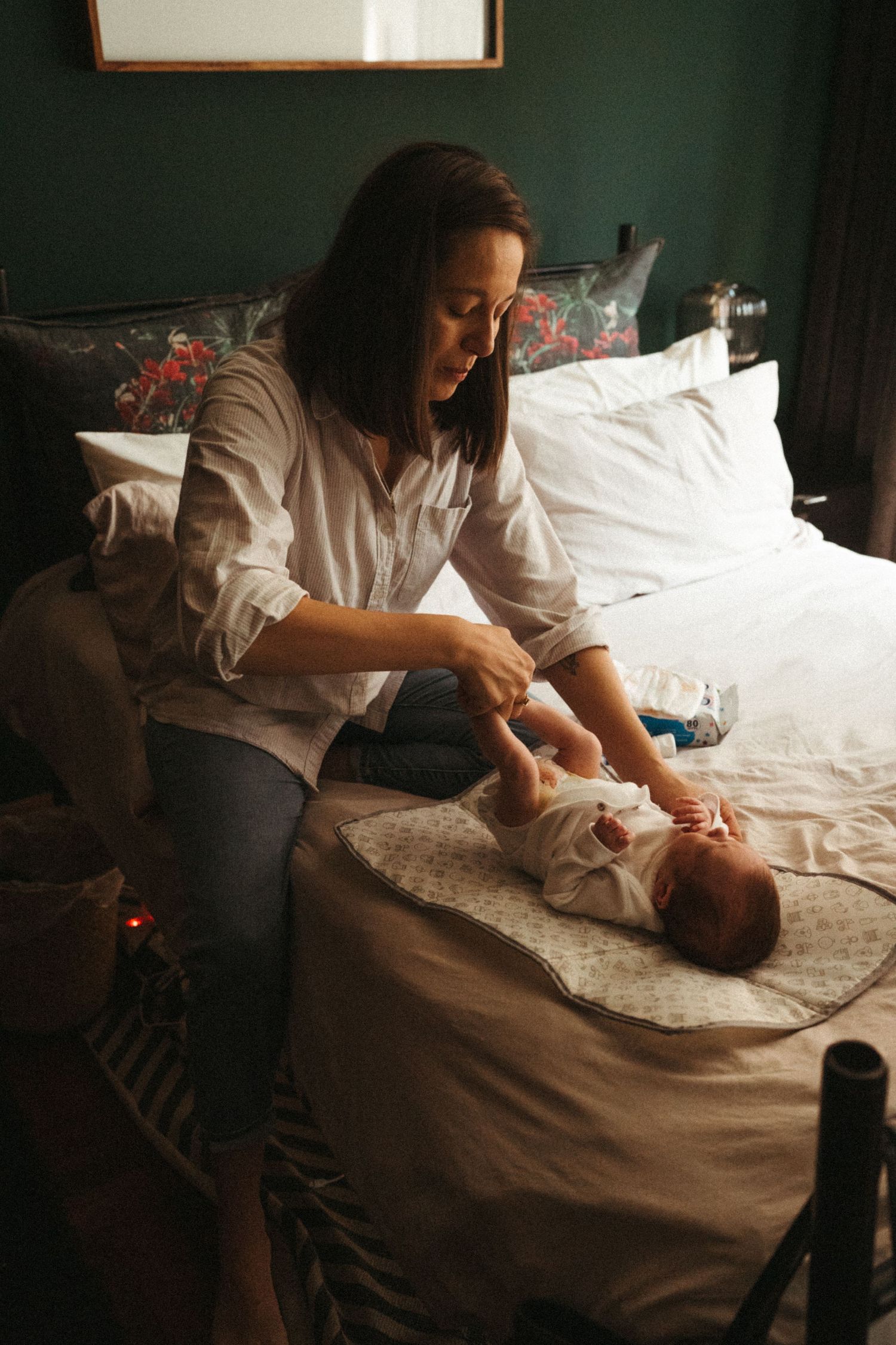 A tender moment captured on a bed with white linens in warm lighting.