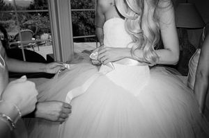 Close-up detail of white tulle wedding dress being adjusted in natural light.