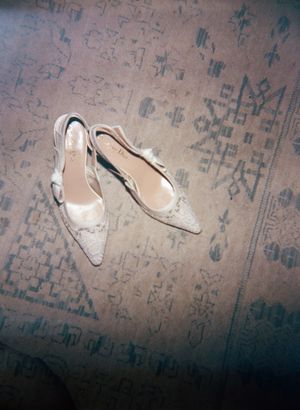 Elegant white bridal shoes displayed on a patterned carpet.