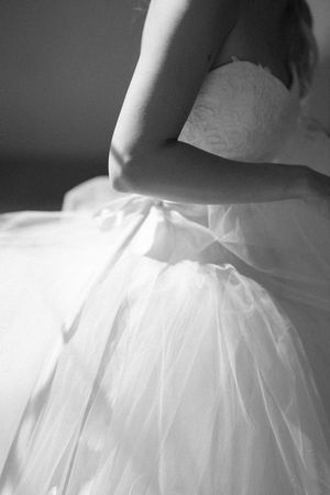 Close-up details of a white tulle wedding dress skirt showing delicate layers and ruffles.
