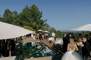 Outdoor wedding venue setup with white tent and chairs against a mountain landscape.