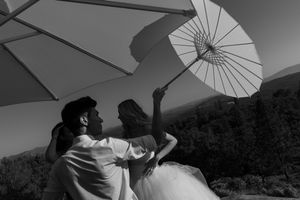 Black and white photo of people holding decorative parasols against a bright sky.