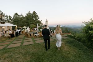 Panoramic view of wedding guests gathering at sunset on hilltop venue.