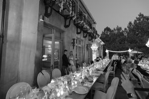A black and white panoramic collage of outdoor dining tables with glowing string lights overhead at dusk.