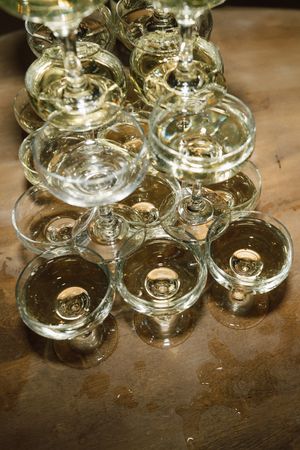 Crystal wine glasses arranged on a wooden surface reflect warm ambient lighting.