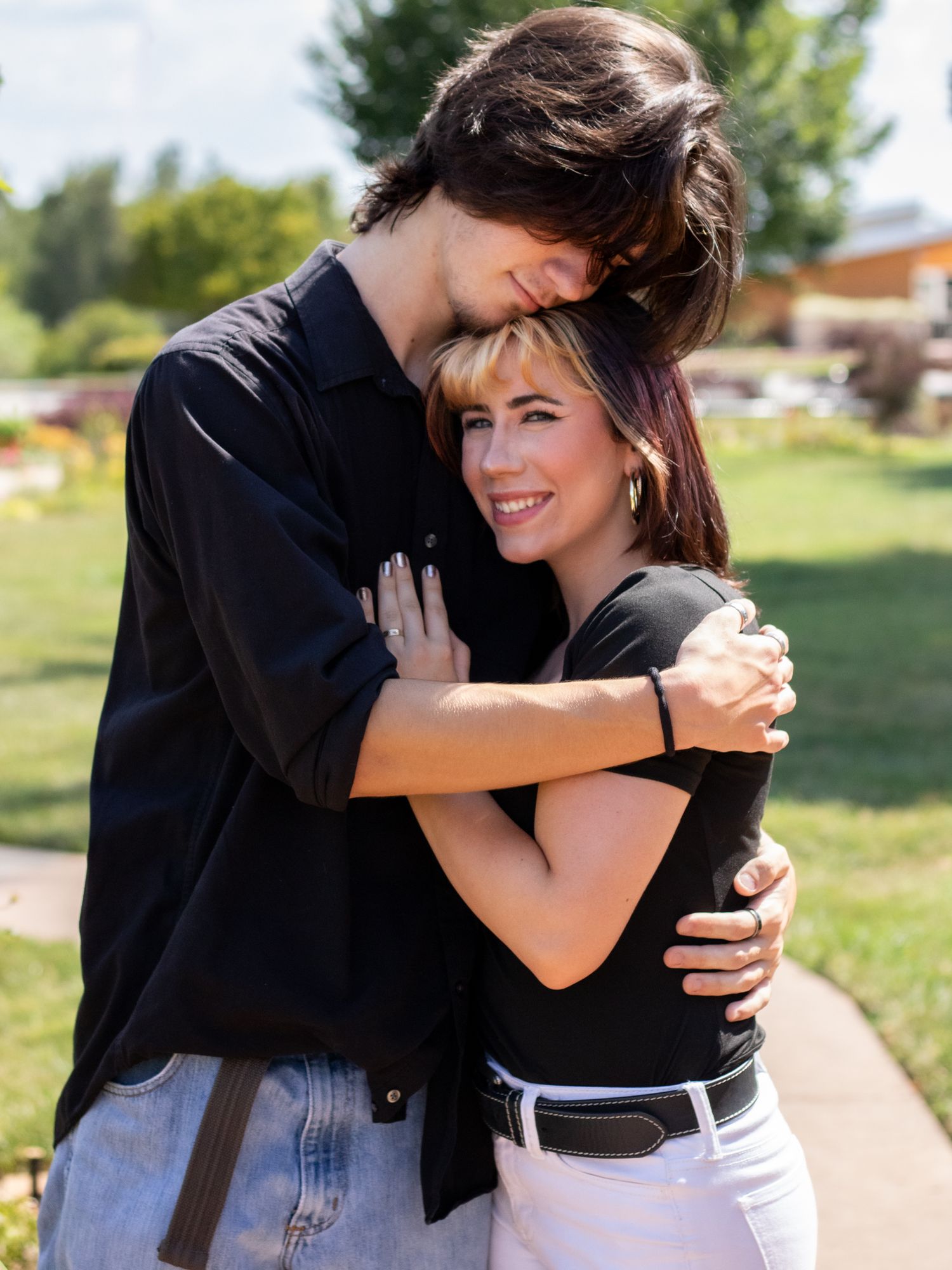 Boyfriend hugging girlfriend while girlfriends' hand is on his chest.