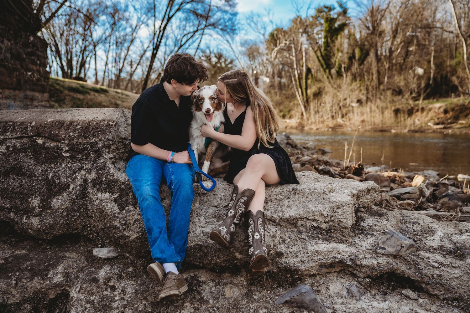 A couple shares intimate moments along a riverbank during their engagement session.