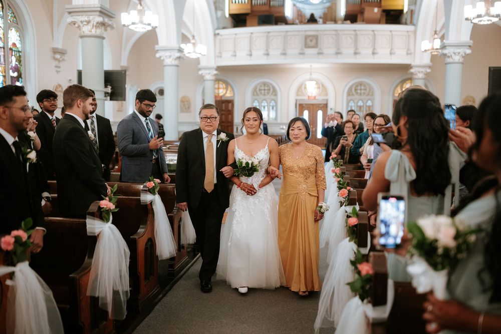 Wedding guests gather in an elegant ballroom with crystal chandeliers during a reception celebration.