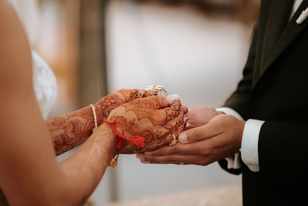Close-up view of hands exchanging wedding rings during a traditional marriage ceremony.