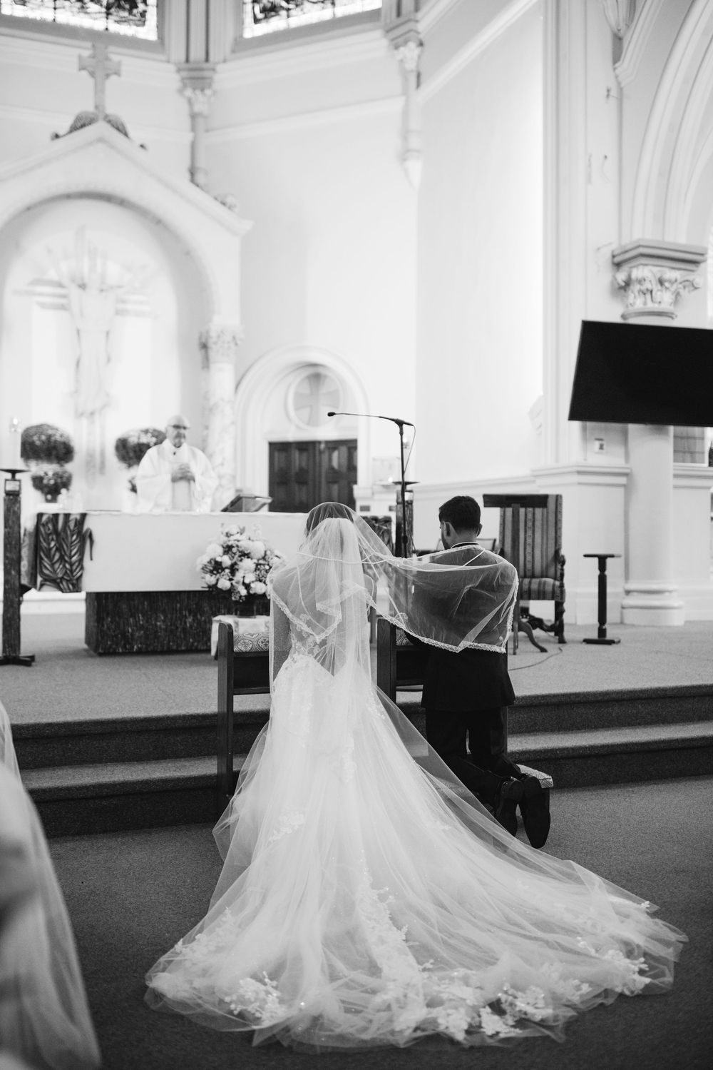 Black and white photo series showing a bride in a flowing wedding gown with long train inside an elegant church sanctuary.