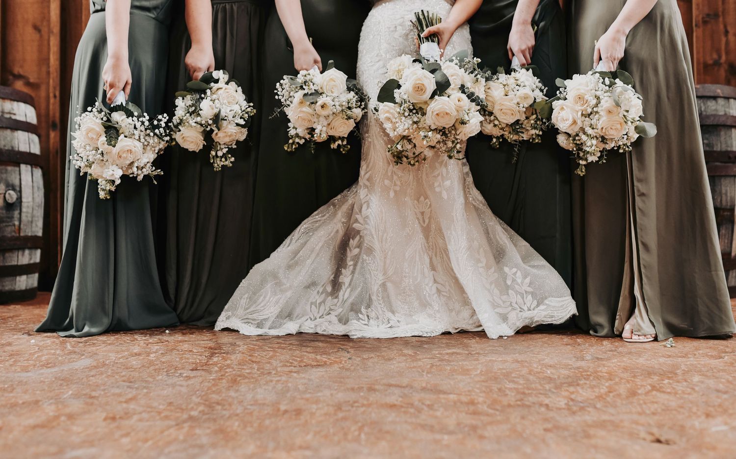 Bridal party in olive and sage green gowns holding ivory bouquets with loose greenery at Lucky Spur Ranch.