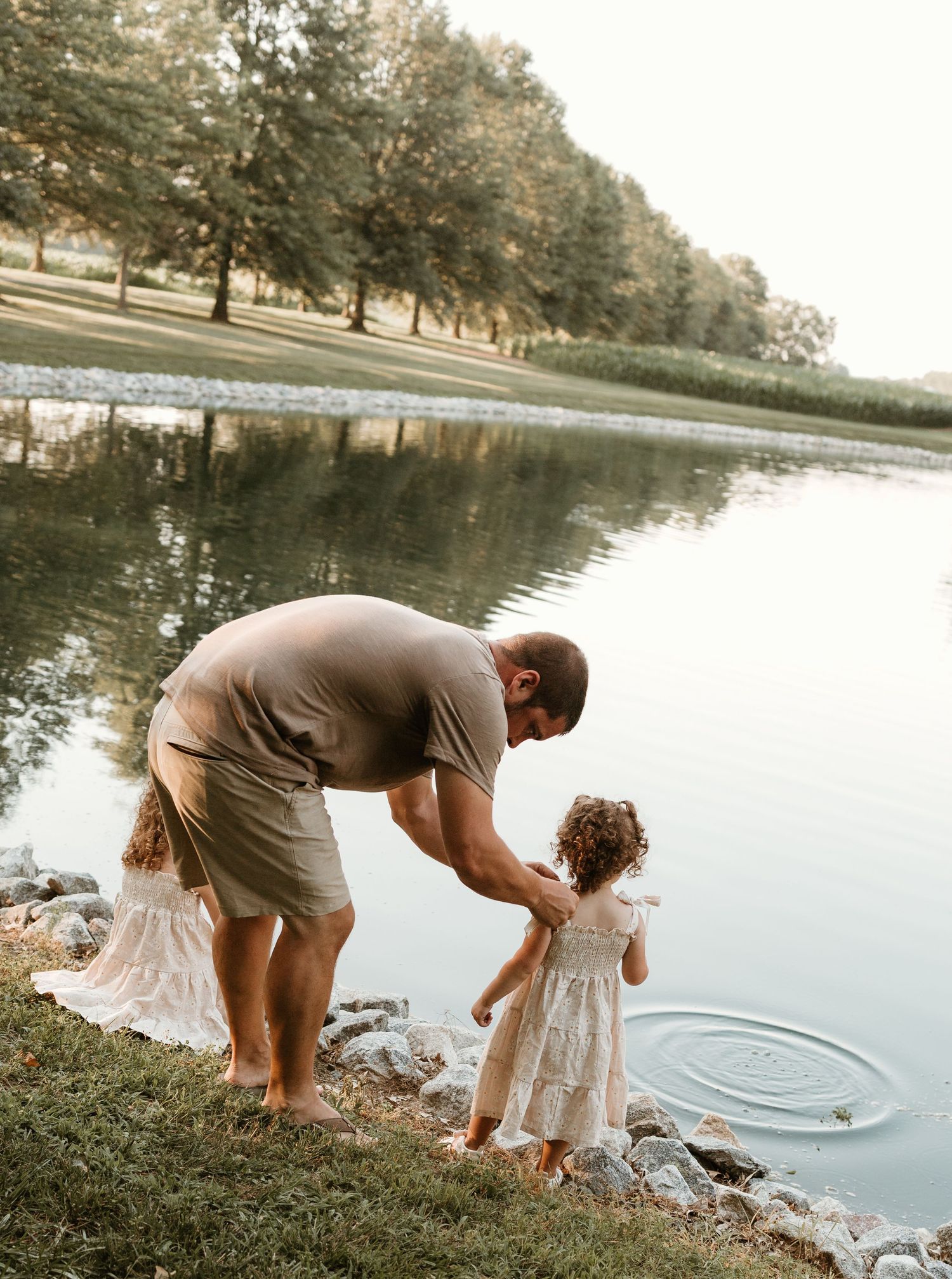 Parent and child explore water's edge together at scenic lake.