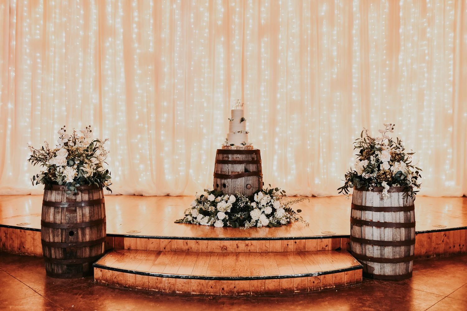 Elegant tiered wedding cake decorated with loose greenery and minimal, modern floral details.