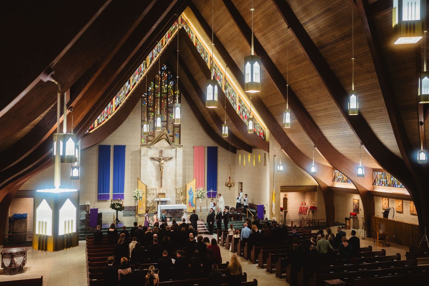 Interior view of a modern church sanctuary with exposed wooden beams and gothic arched windows along the walls.